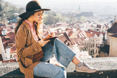 Woman in brown hat writing in the diary in view point with amazing view. 