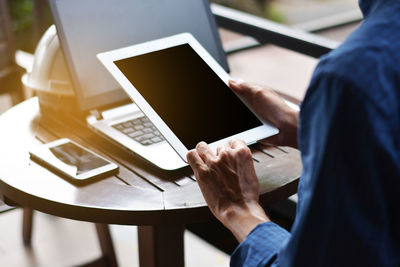 Midsection of man using mobile phone on table