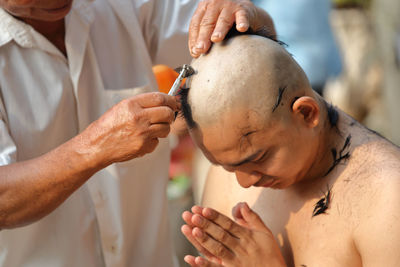 Man cutting hair of monk during ordination