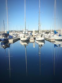 Sailboats moored on lake against clear blue sky