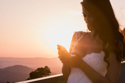 Close-up of woman standing against sky during sunset