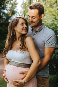 Husband embracing pregnant wife outdoors