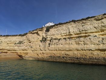 Rock formations by sea against blue sky