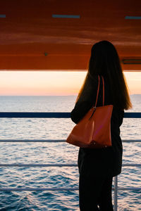 Side view of woman standing by railing in boat on sea