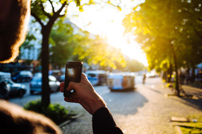 Close-up of hand holding smart phone on road