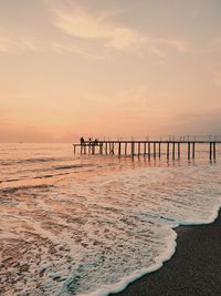 Pier on sea against sky during sunset