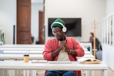 Tired sleepy black guy student in headset stretch on chair exhausted after long time study at laptop