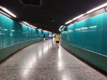 Rear view of people walking in illuminated tunnel