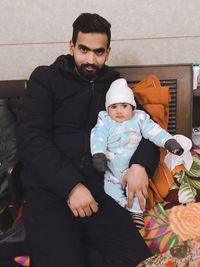 Full length portrait of father and baby sitting outdoors