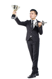 Portrait of man with arms raised standing against white background