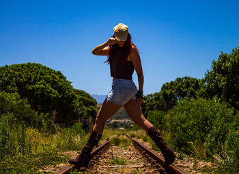 Full length of young woman standing against trees
