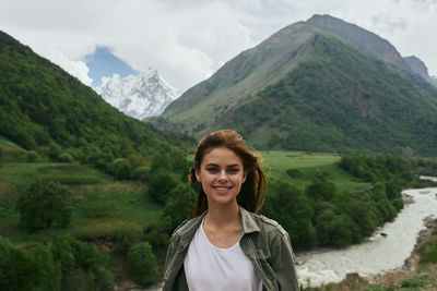 Portrait of young woman standing against mountain