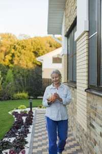 Smiling senior woman with harvested pumpkin in the garden