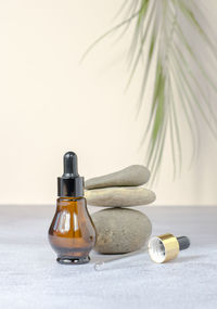 a brown cosmetic bottle and a dropper on a beige background with a green branch.