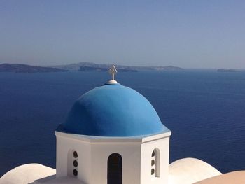 Cross in sea against clear blue sky