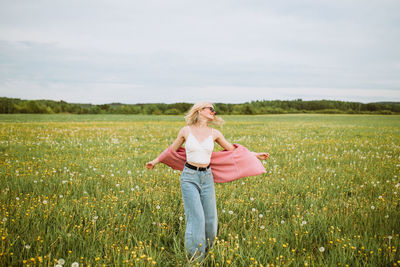 Happy young female standing in meadow in summer