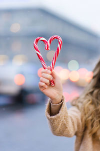 A heart made of two candy canes in the hands of a girl. the concept of the valentine's day holiday