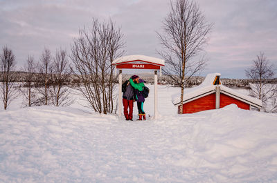 People on snow covered field against sky