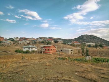 Houses on field by mountain against sky