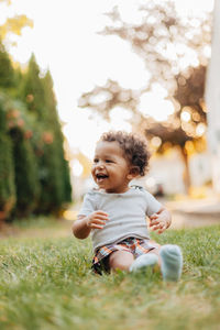 Smiling boy looking away while sitting at lawn