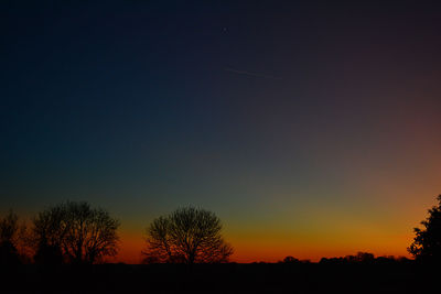 Scenic view of silhouette trees against clear sky at sunset