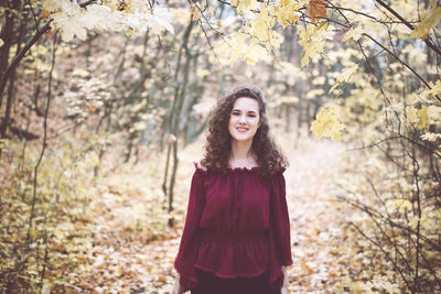 Young woman standing against trees