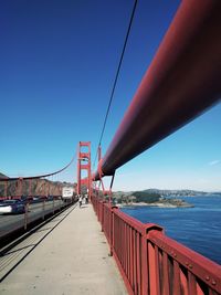 Suspension bridge over river against blue sky