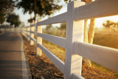 Close-up of railing by fence against sky