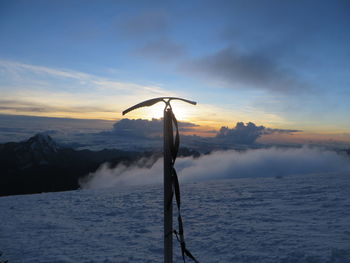 Silhouette ice axe on snow covered field against sky