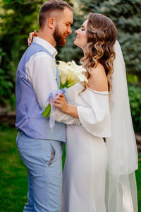 Newlywed couple embracing while standing outdoors