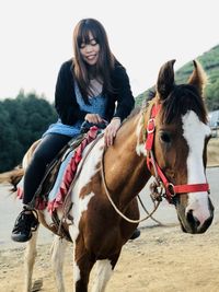 Smiling young woman riding horse