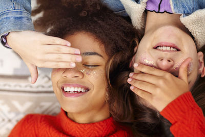 Close-up of friends lying down while covering eyes