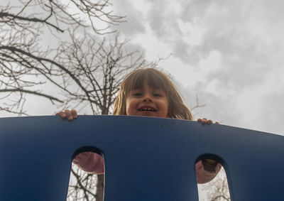 Portrait of happy girl playing in car against sky