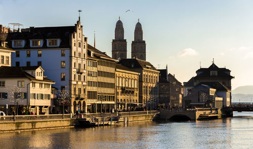 Bridge over river by buildings against sky in city