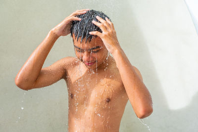 Full length of shirtless man in bathroom