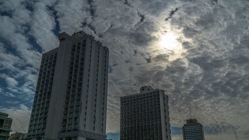 Low angle view of skyscrapers against cloudy sky