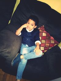 High angle portrait of boy lying on sofa at home