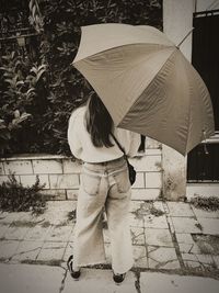 Shadow of woman holding umbrella on footpath during rainy season