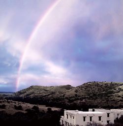 Rainbow over landscape against cloudy sky