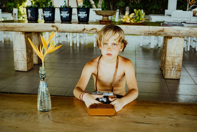 Portrait of shirtless boy with camera