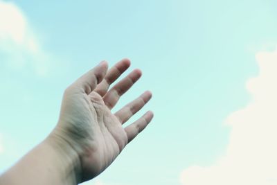 Cropped hand reaching blue sky