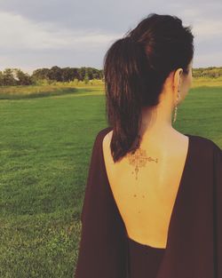 Rear view of woman standing on field against sky