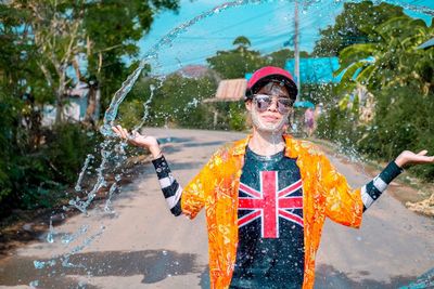 Water splashing on young woman standing on road