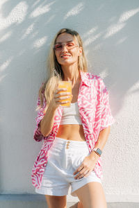 Young woman standing against wall
