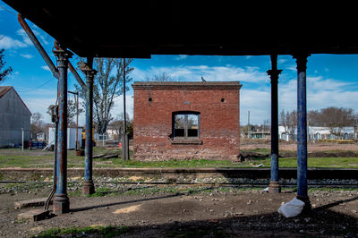 Abandoned building by trees on field against sky