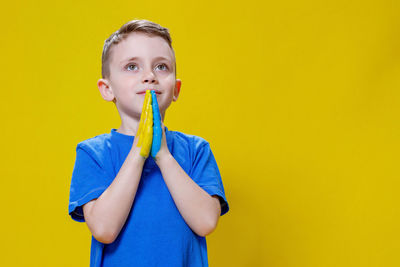 Portrait of young woman holding lollipop against yellow background