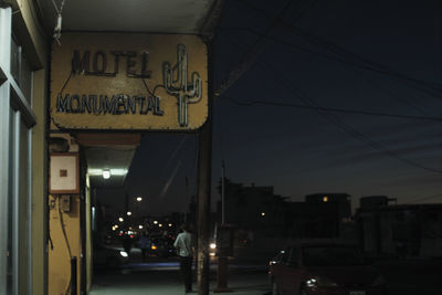 Illuminated road sign on street in city at night
