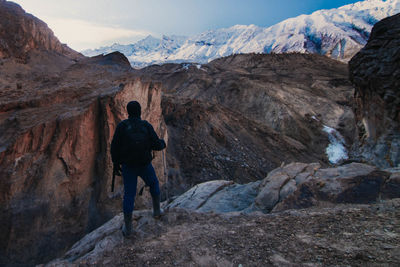 Rear view of man climbing on mountain against sky