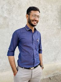 Portrait of young man standing against wall