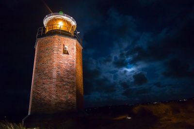 Low angle view of illuminated lighthouse against sky at night